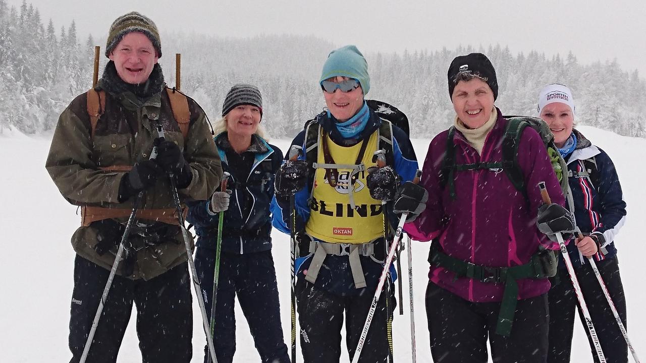 Bilde som Noen i turgjengen stående mens snøen virvler rundt dem.