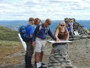 Bildet viser flere som studerer sikteplata. I bakgrunnen ser vi varden på Smørlifjell.