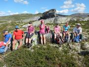 Bilde av gruppen sittende i en steinsatt skråning når de tar en rast i strålende sommervær.