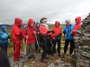 Gruppen ser på steinrøys og er ikledt regntøy da det blåste og regnet litt.