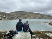 Rast ved fjellvann: Tore og Jarle sitter med ryggen til på stor stein.