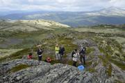 Bildet viser syv personer tatt litt ovenifra. En ser fjellheimen i bakgrunnen med store områder dekket av lav.